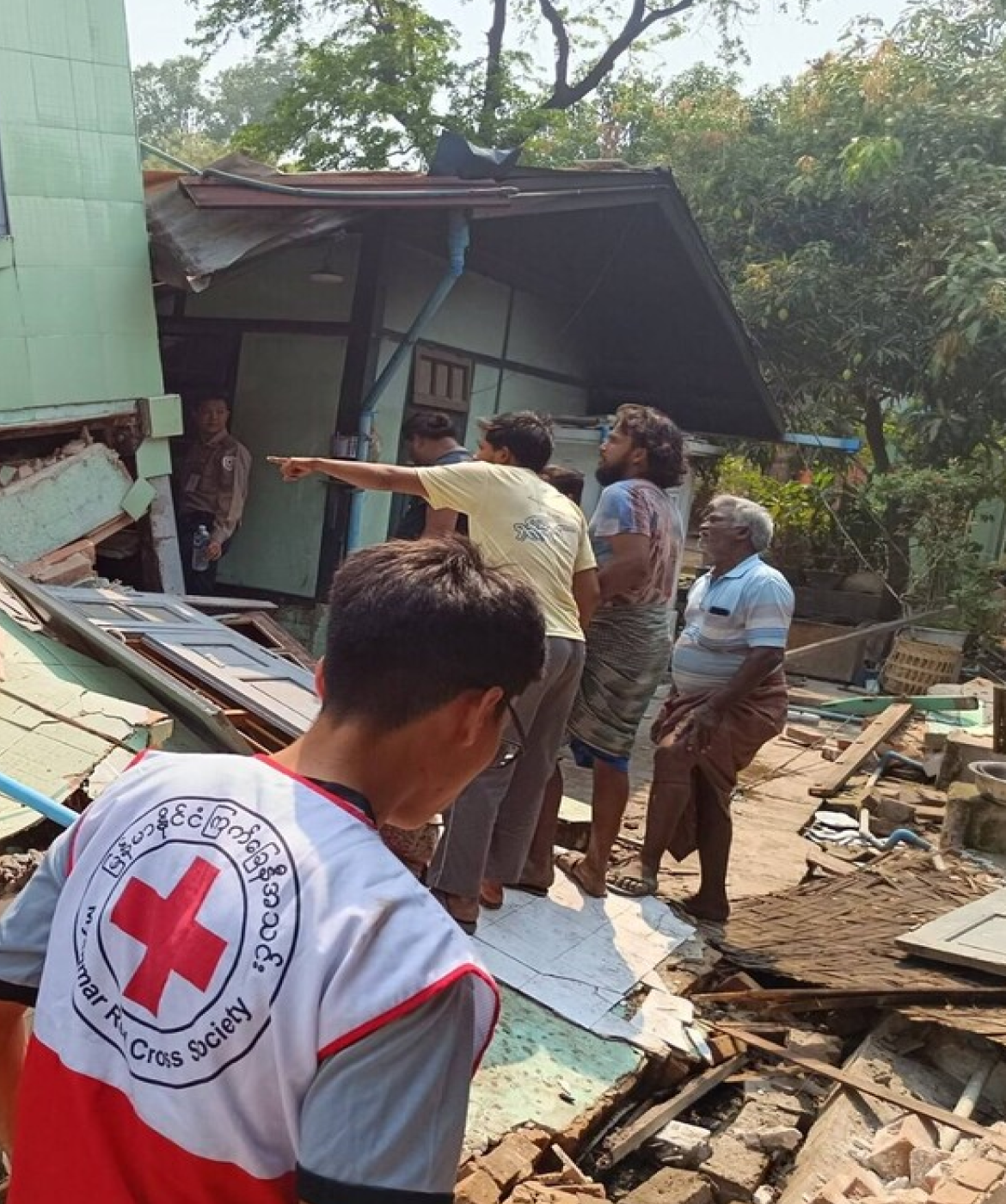 Red Cross staff and volunteers inspect a collapsed building in Myanmar, assessing damage following earthquake.