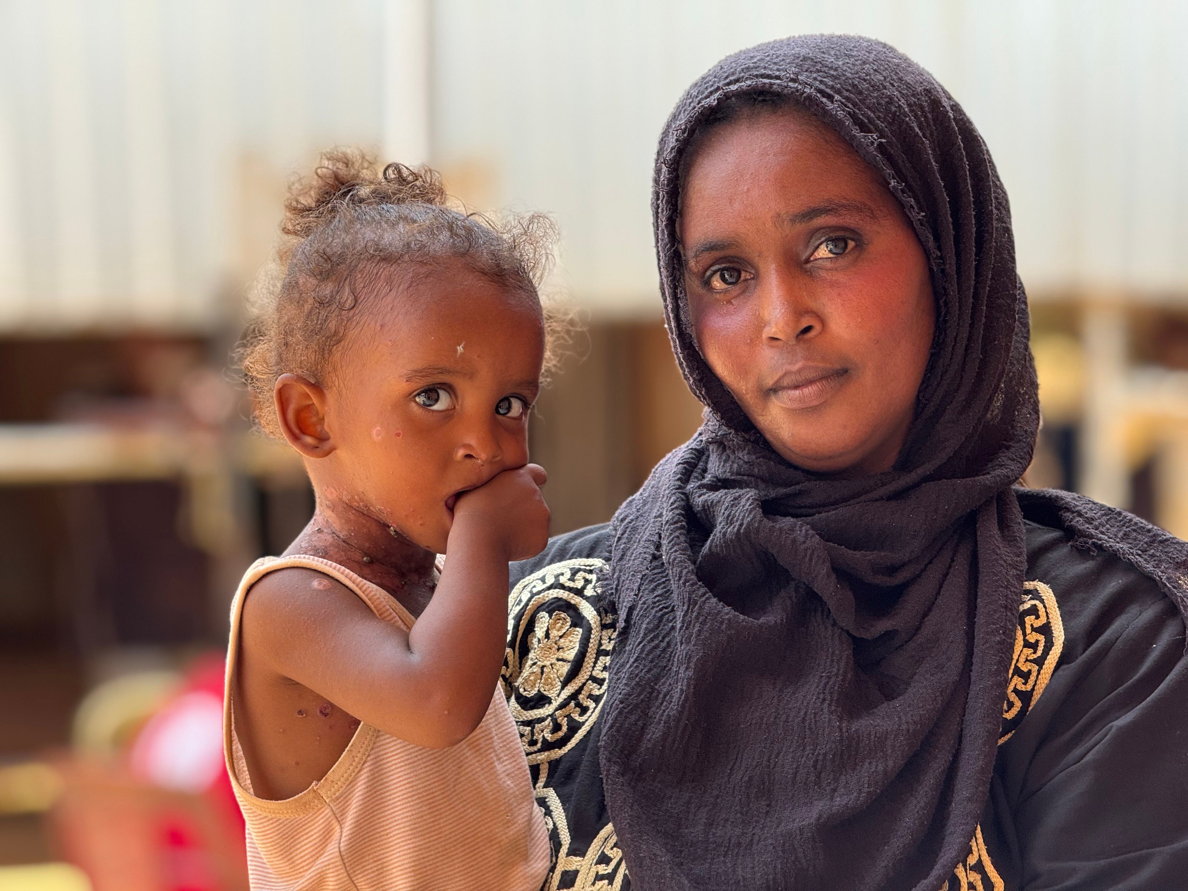 A woman with holds a young child closely in a shelter where they are receiving support.