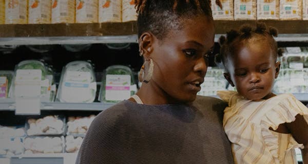 A woman holding a child in a supermarket.