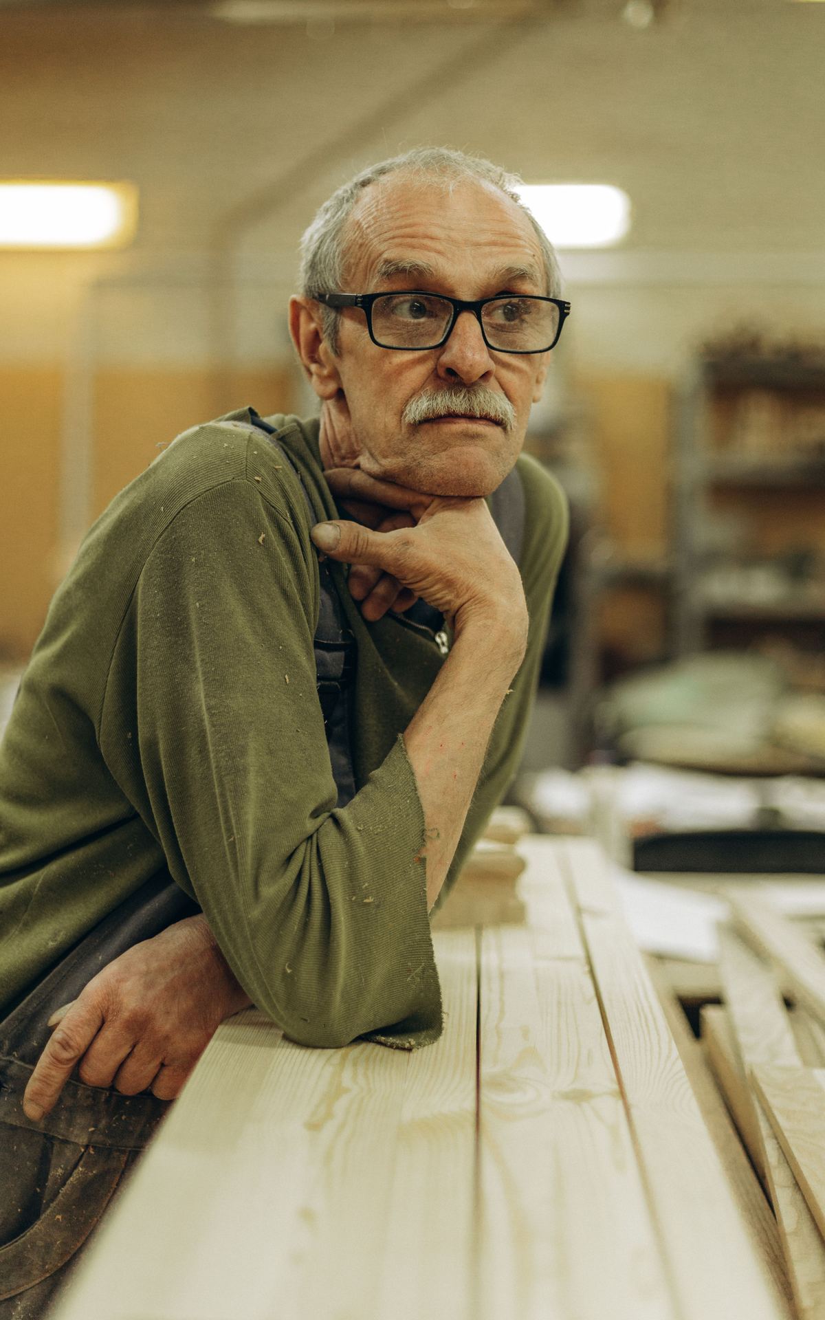 Artisan âgé accoudé à son établi