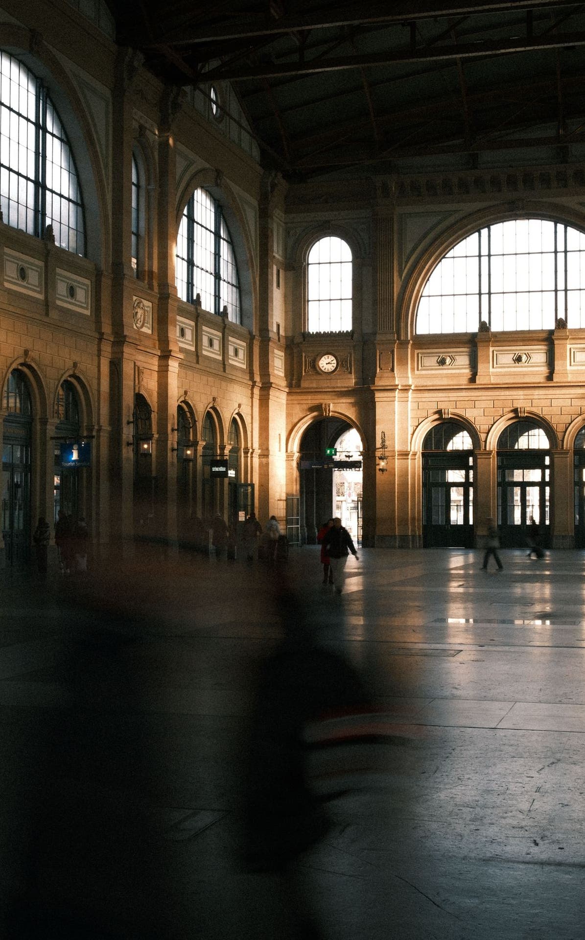 Hall de gare monumental et voyageurs en mouvement