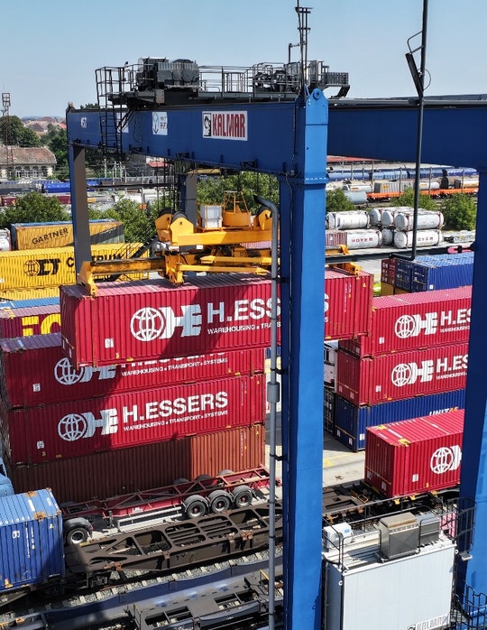Aerial view of a busy freight terminal with colorful shipping containers and a blue gantry crane.
