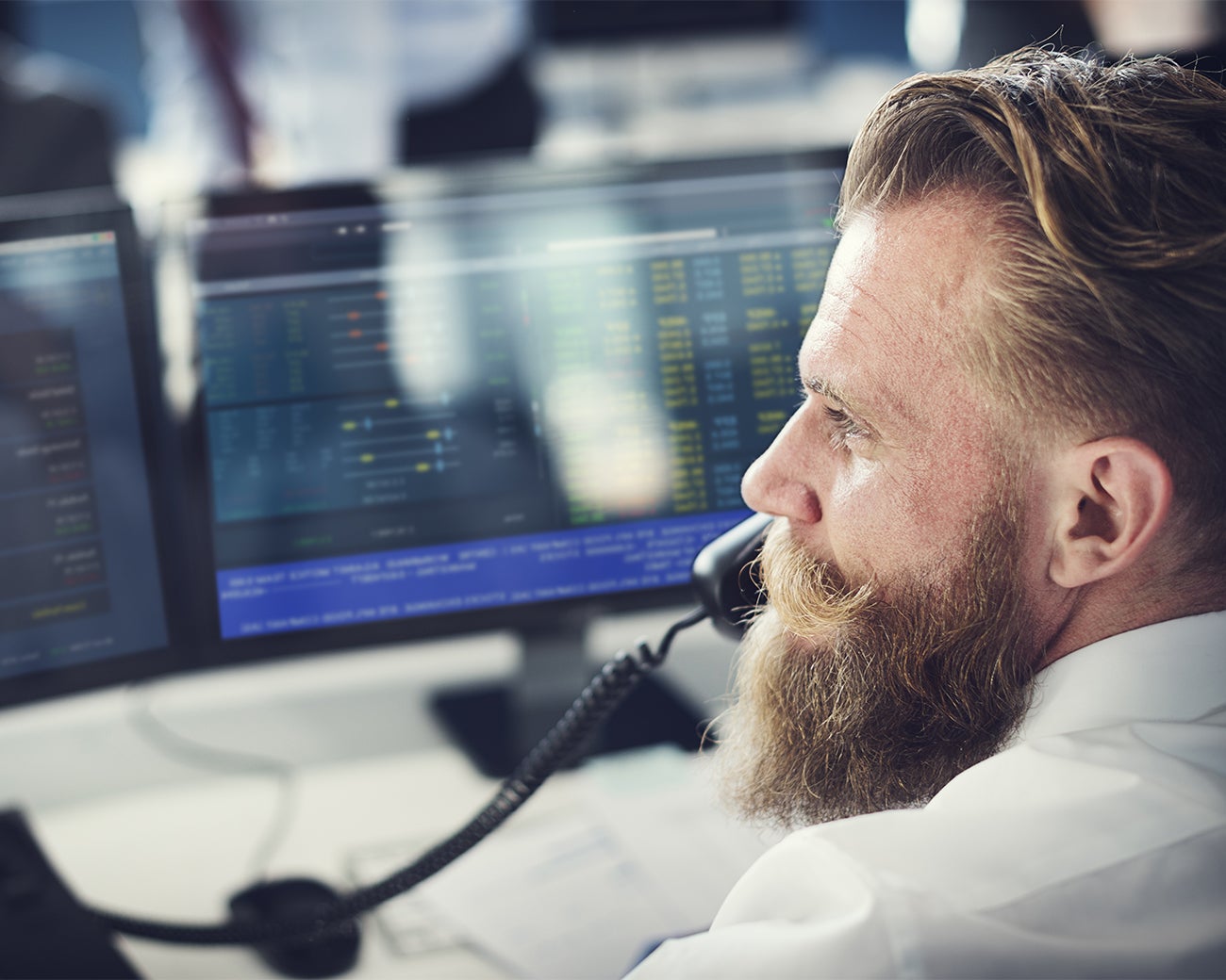 Man aan de telefoon achter beeldschermen met data