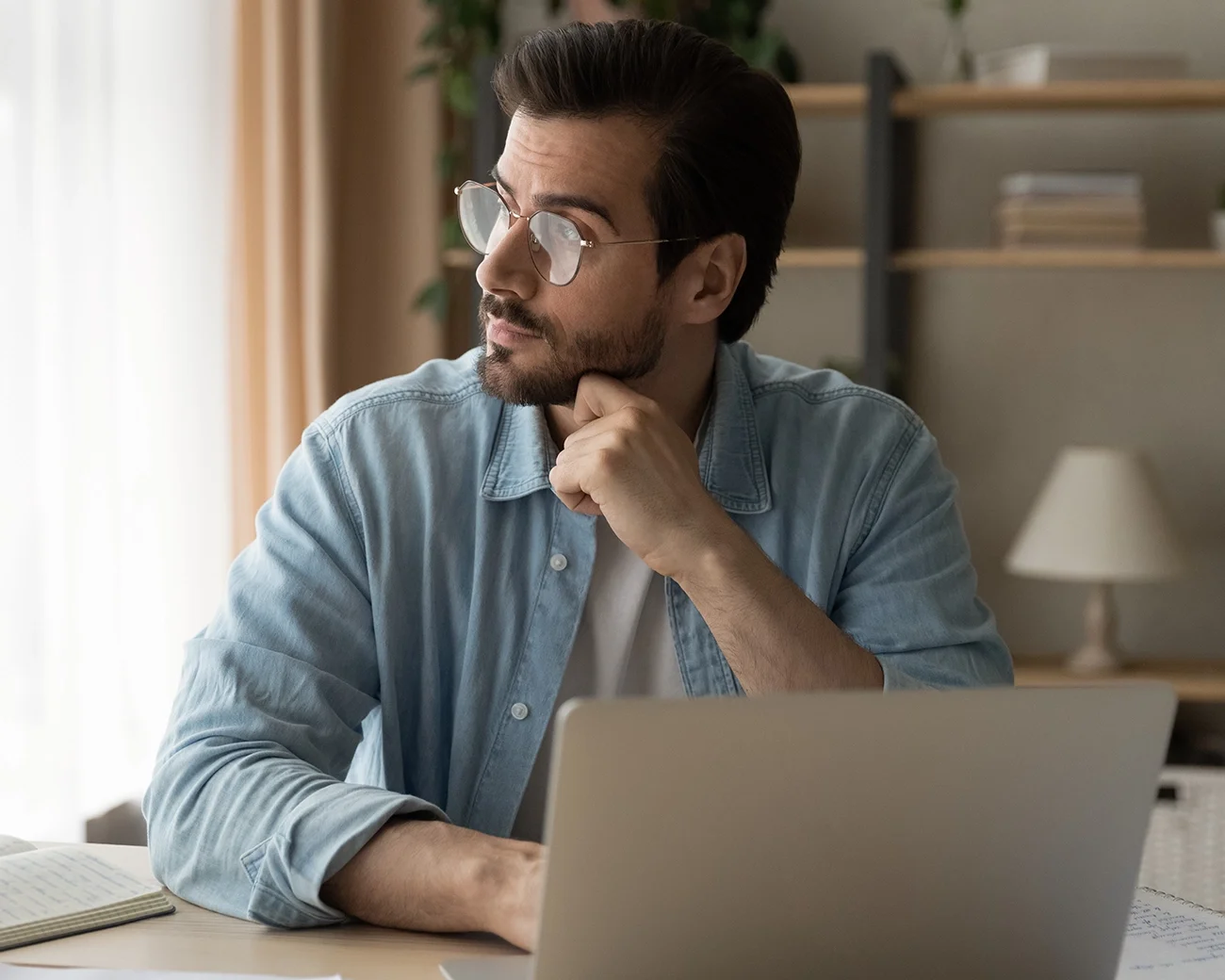 man met laptop kijkt naar links uit het raam
