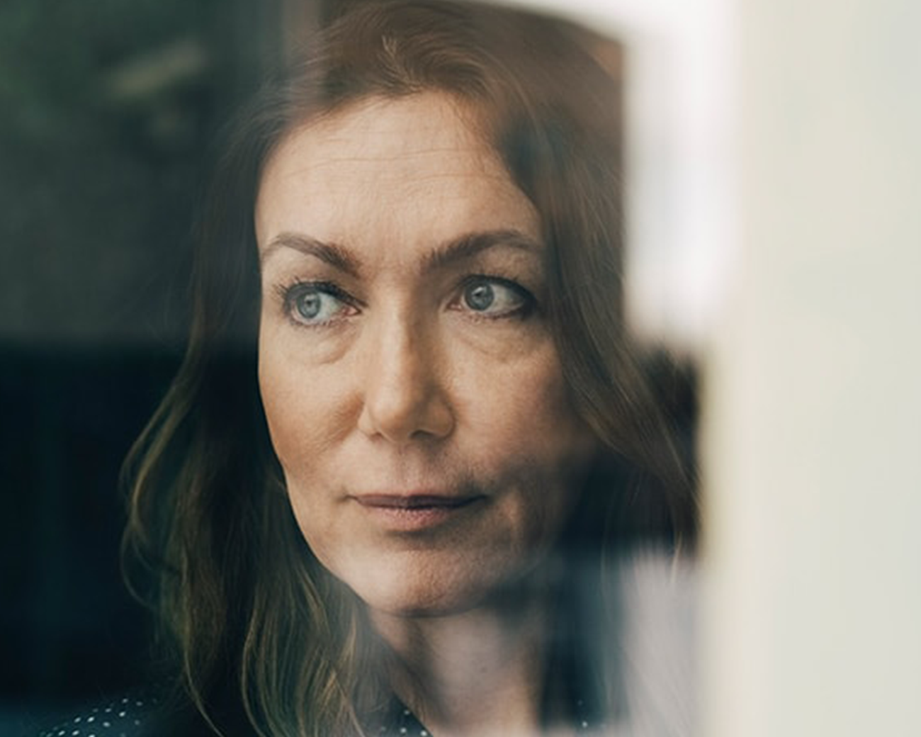 Vrouw kijkt door een raam opzij