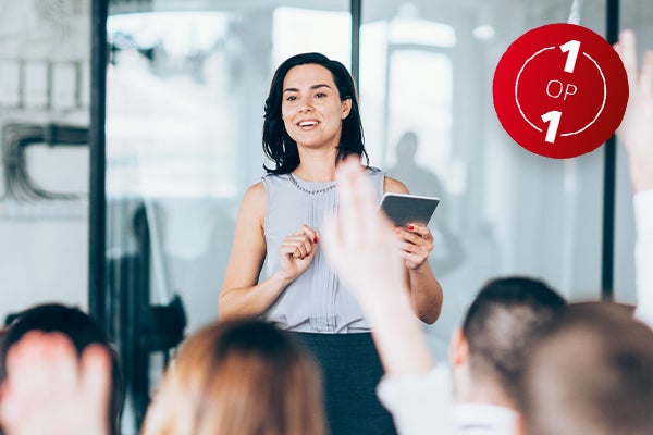 Vrouw met notitieblok staat voor een groep mensen en kijkt rond