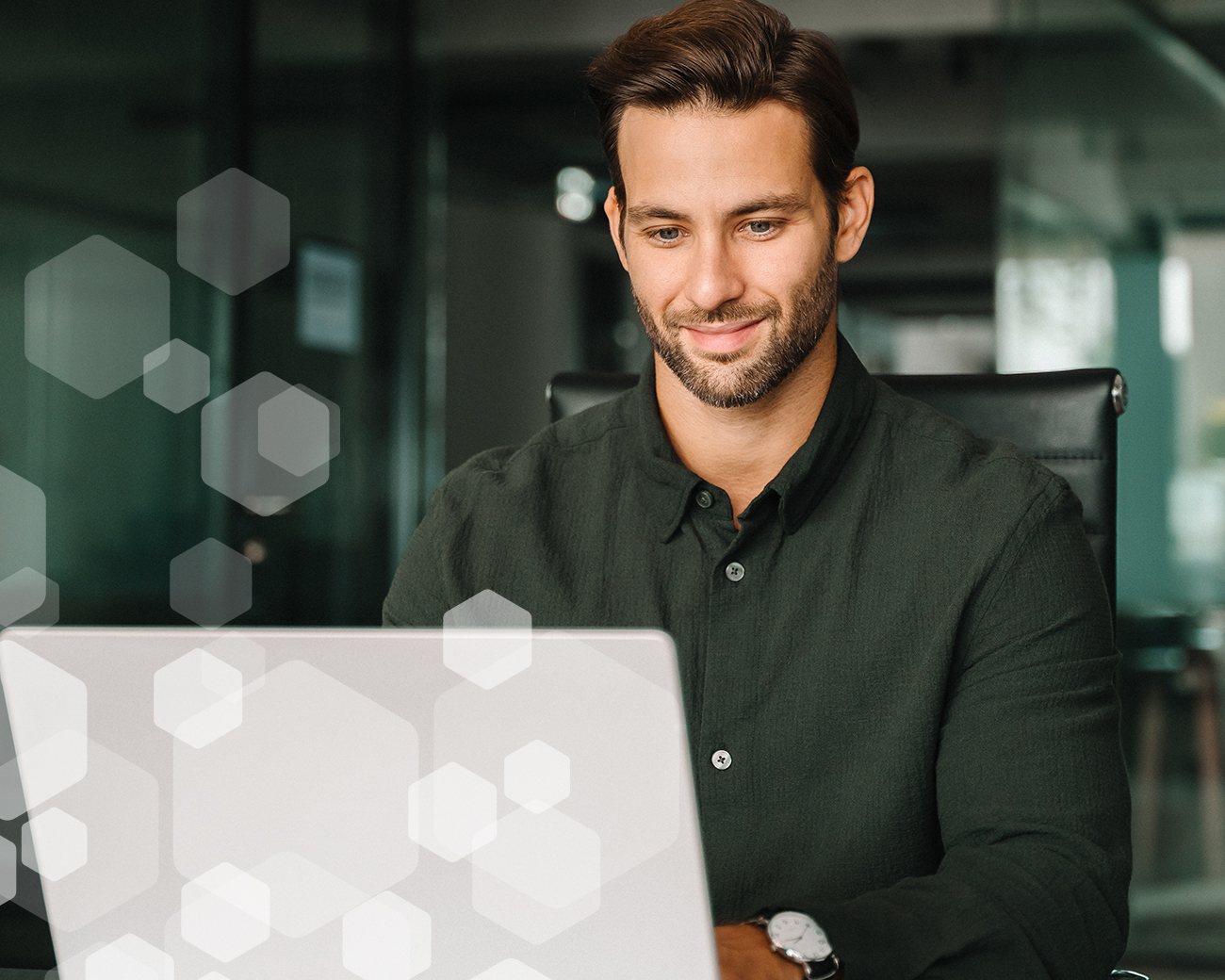 Man met groene blouse zit glimlachend achter laptop
