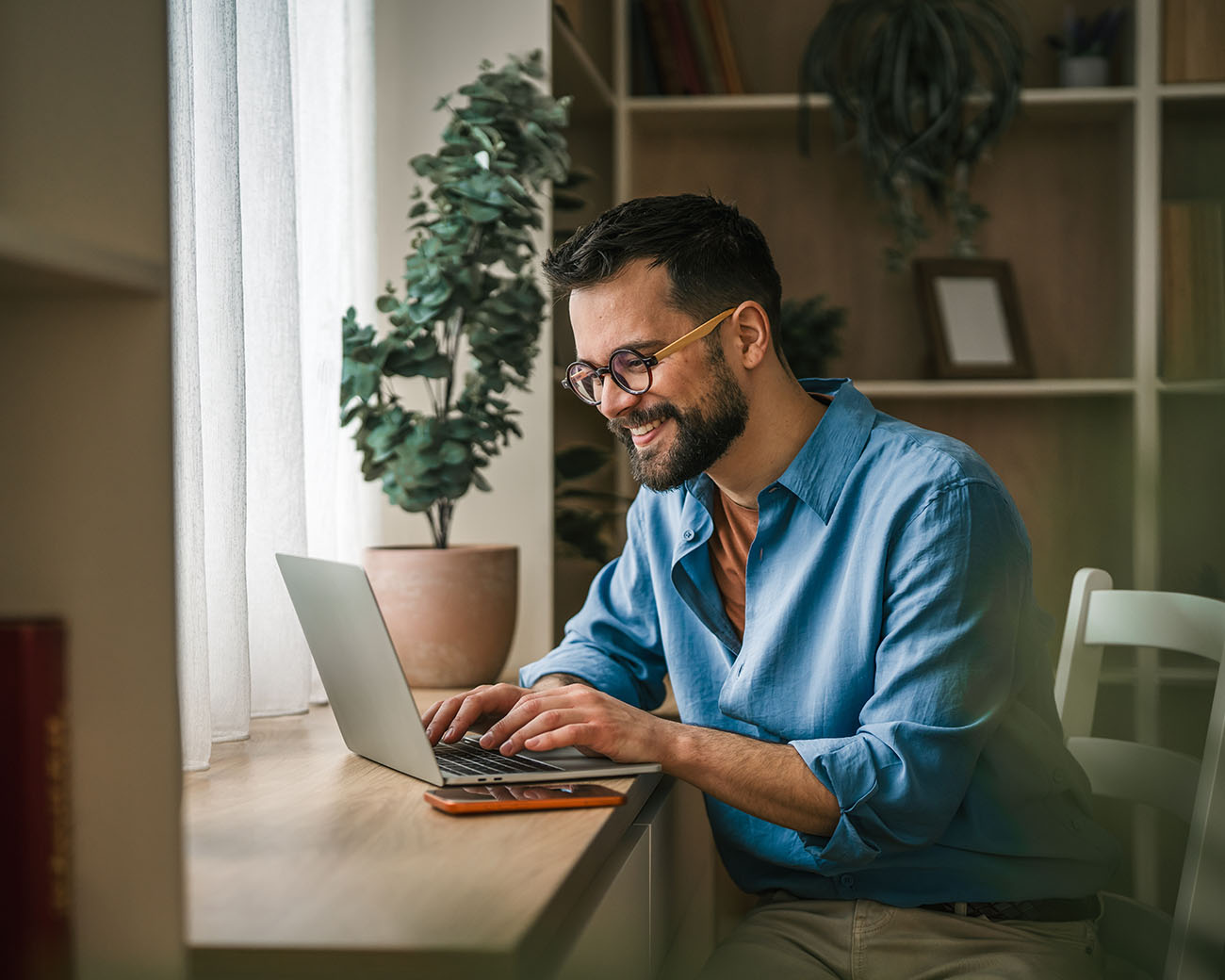 Man met bril zit vrolijk achter laptop