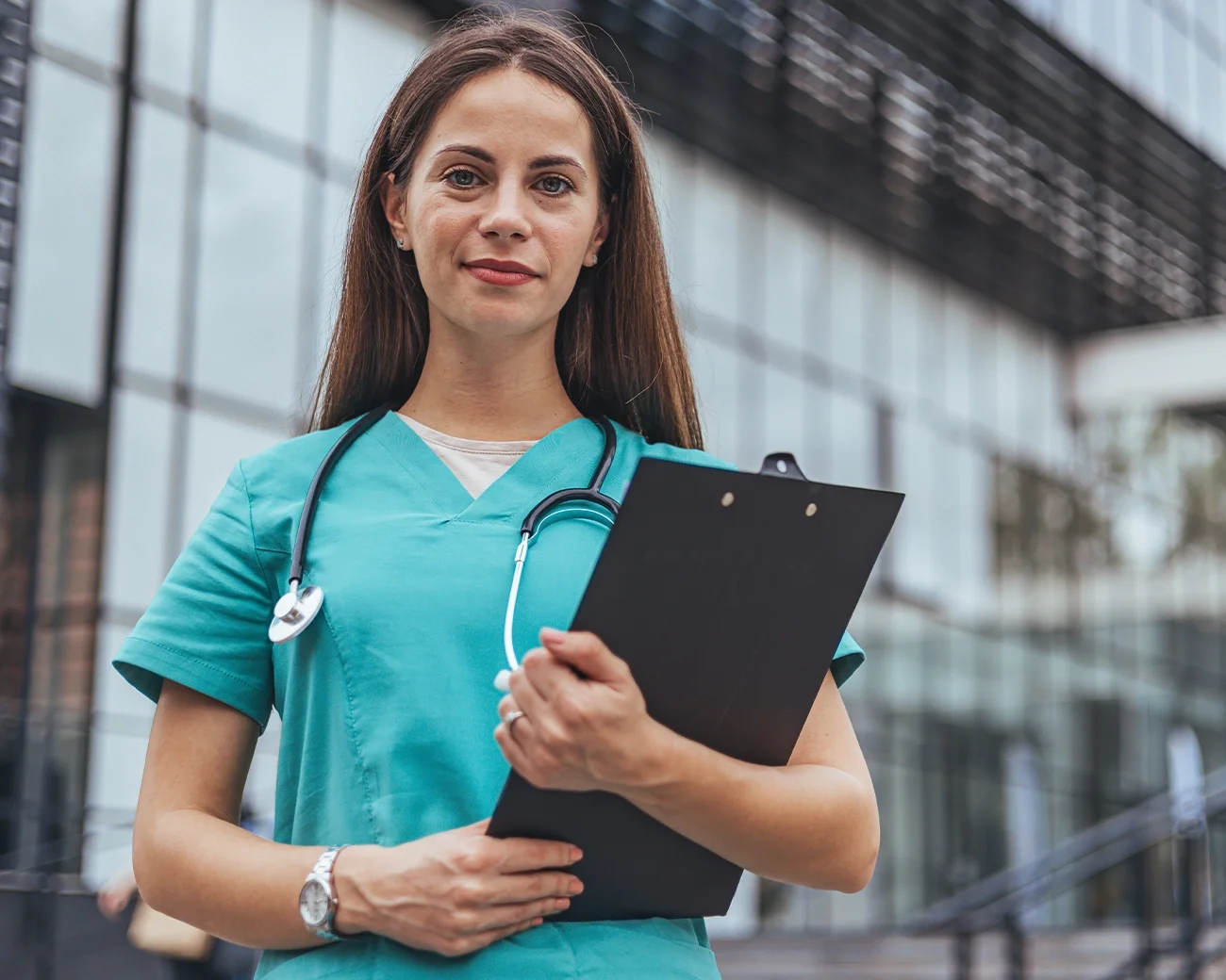 Verpleegster met notitieblad buiten voor een zorginstelling