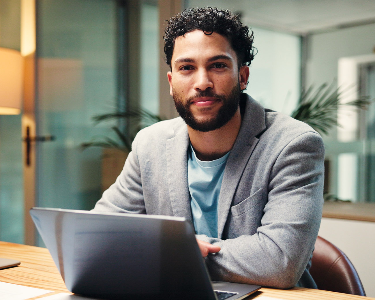 Man op kantoor glimlachend achter laptop