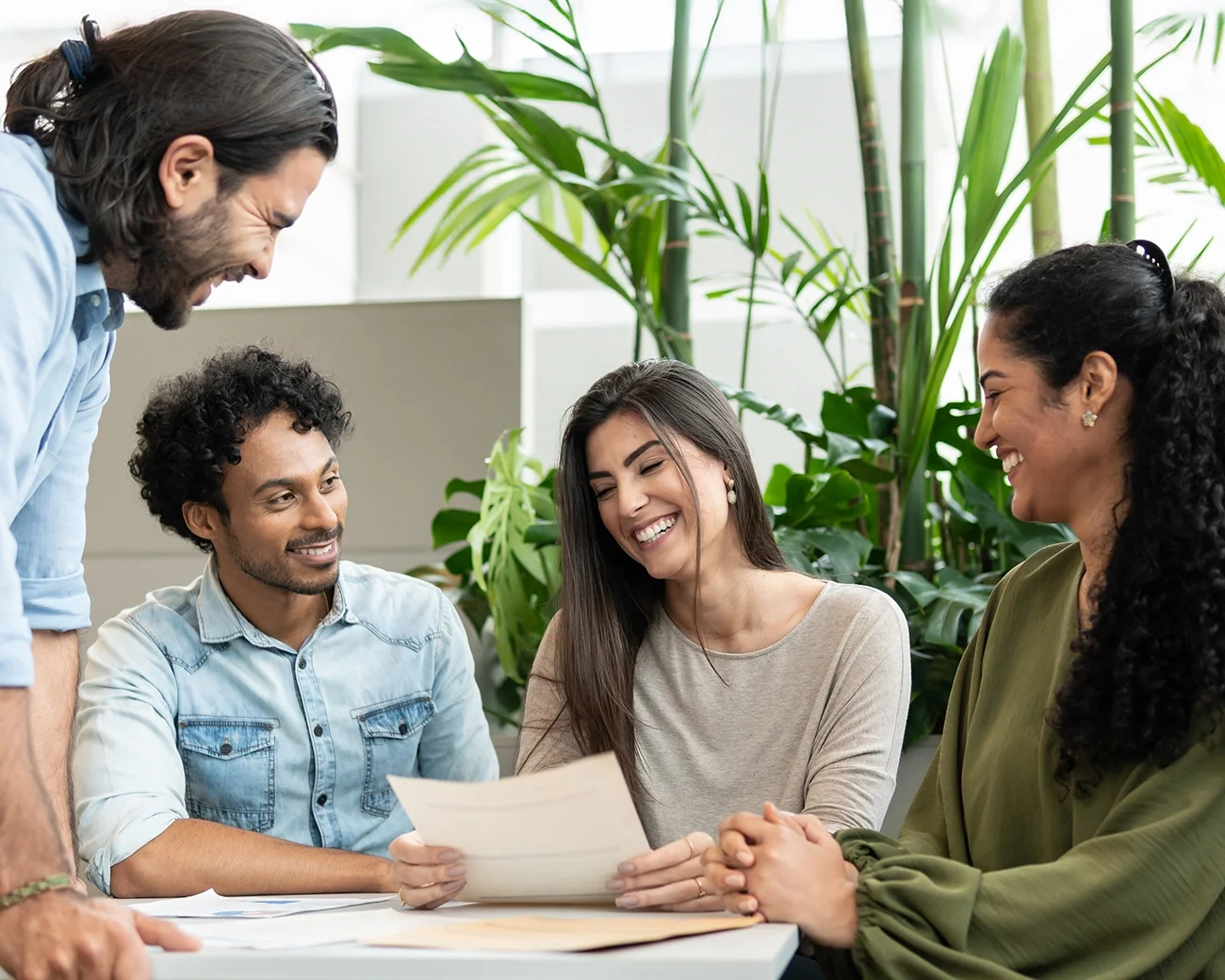 Vier mensen zitten lachend aan een bureau