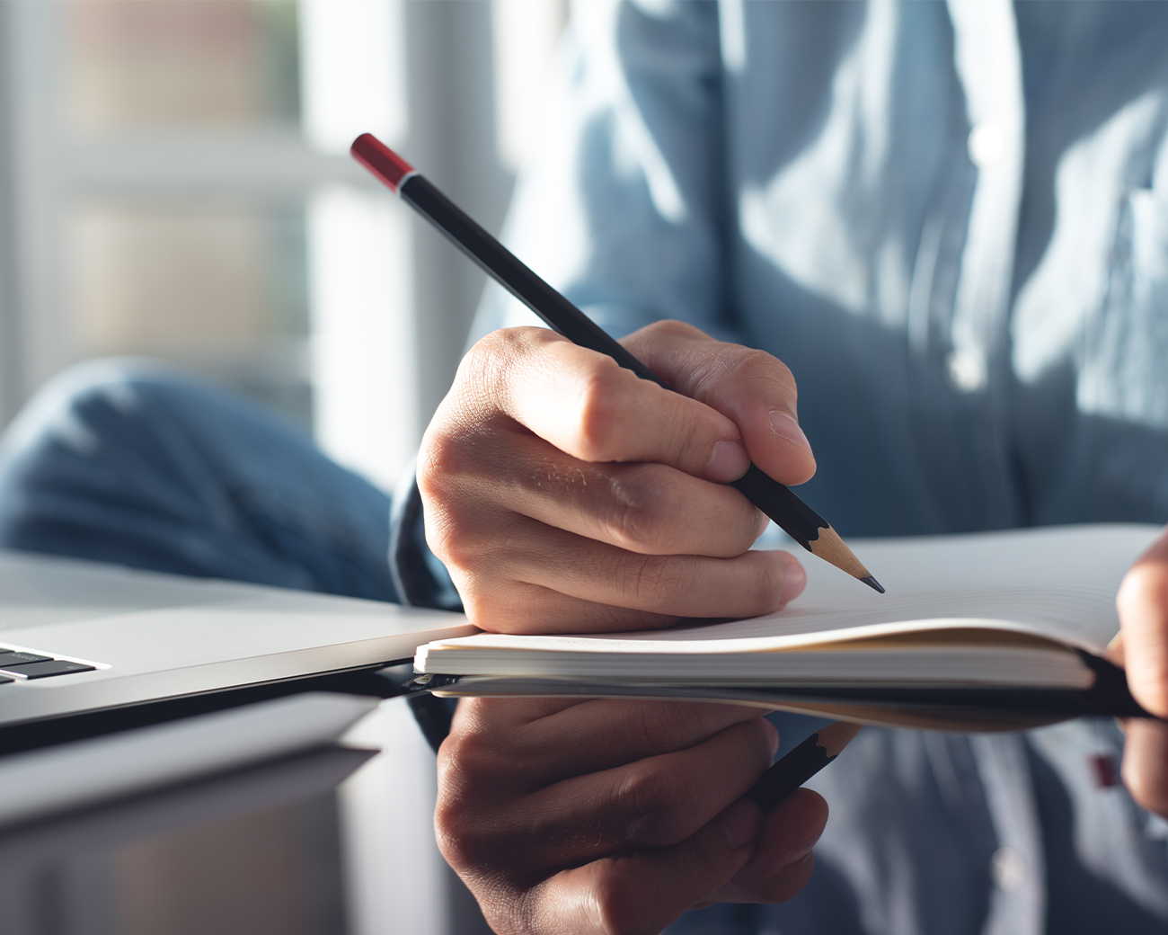 Bedrijfskundige schrijft in schrift met laptop