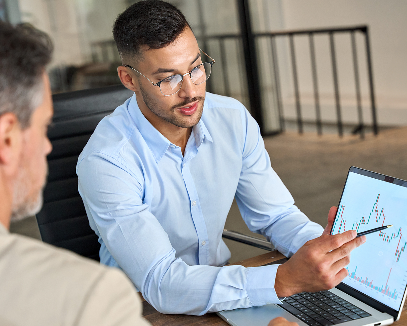 Twee mannen kijken samen naar een laptop en bespreken een grafiek die op de laptop is te zien.