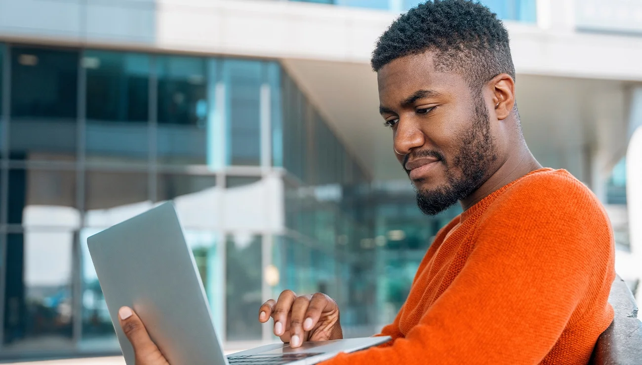 man oranje shirt met laptop