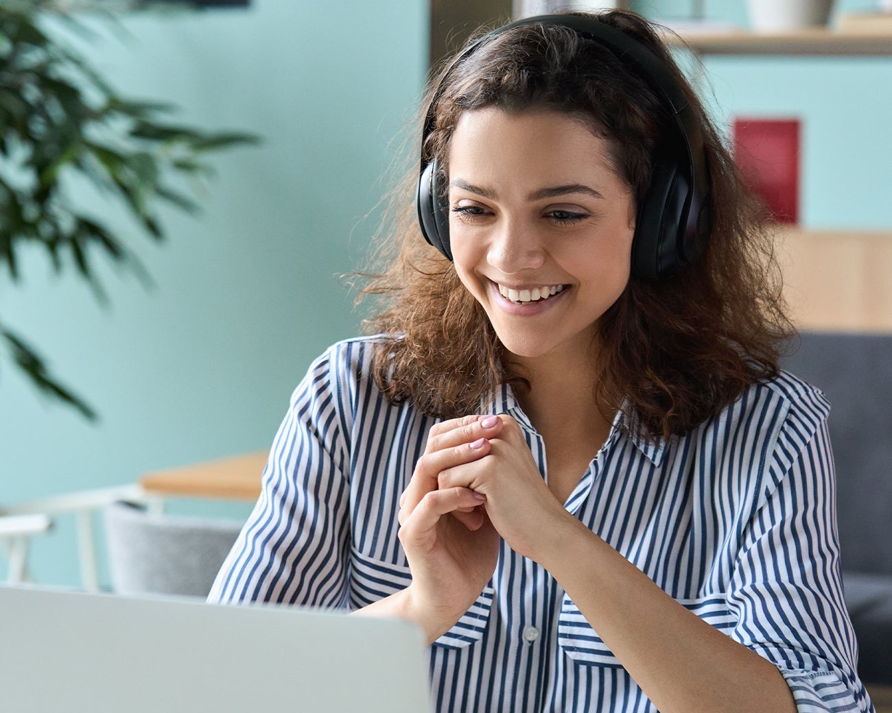 Lachende vrouw met koptelefoon achter laptop