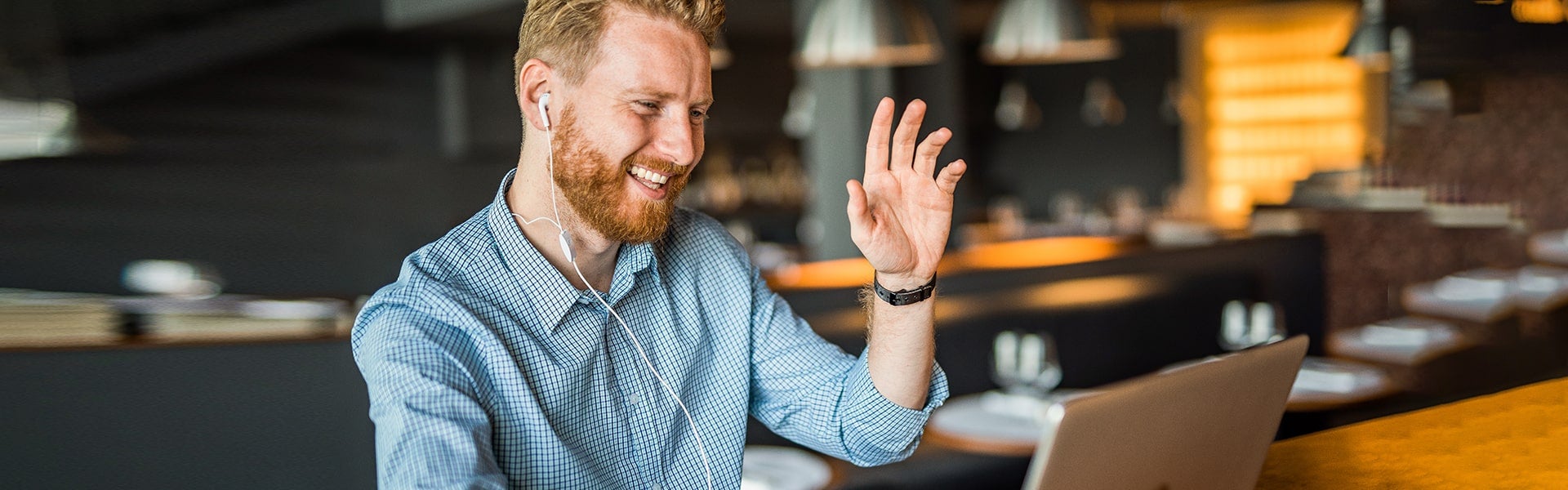 Man zwaait naar laptop met oortjes in