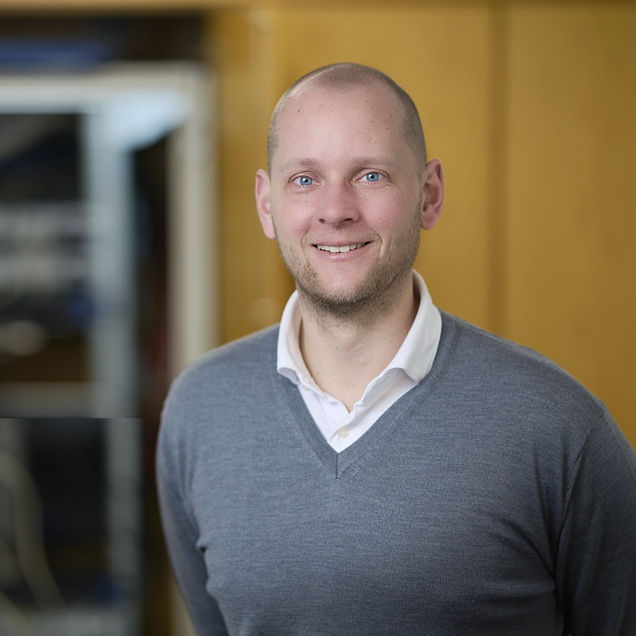 Portret van ISBW-student Chris Helwerda in een grijs shirt op een donkergele achtergrond