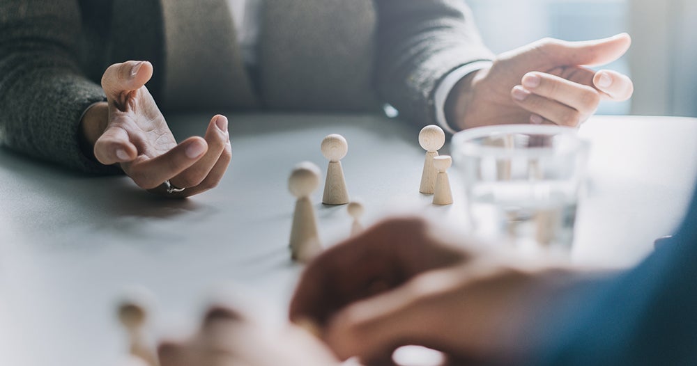 Twee overleggende personen met pionnen op tafel