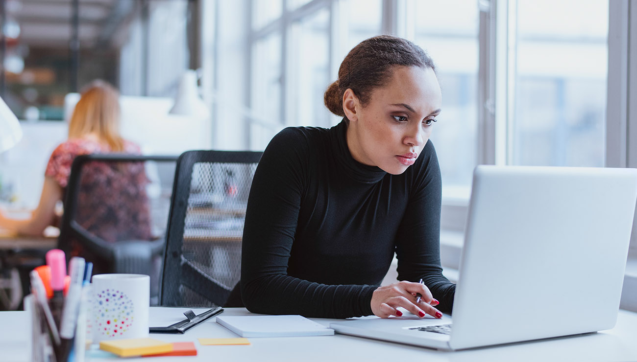 Vrouw, zwarte coltrui achter laptop