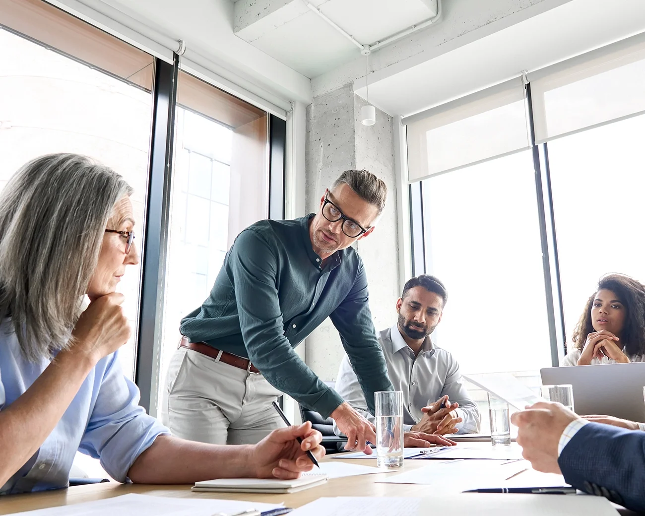 Man met bril in gesprek met mensen aan tafel