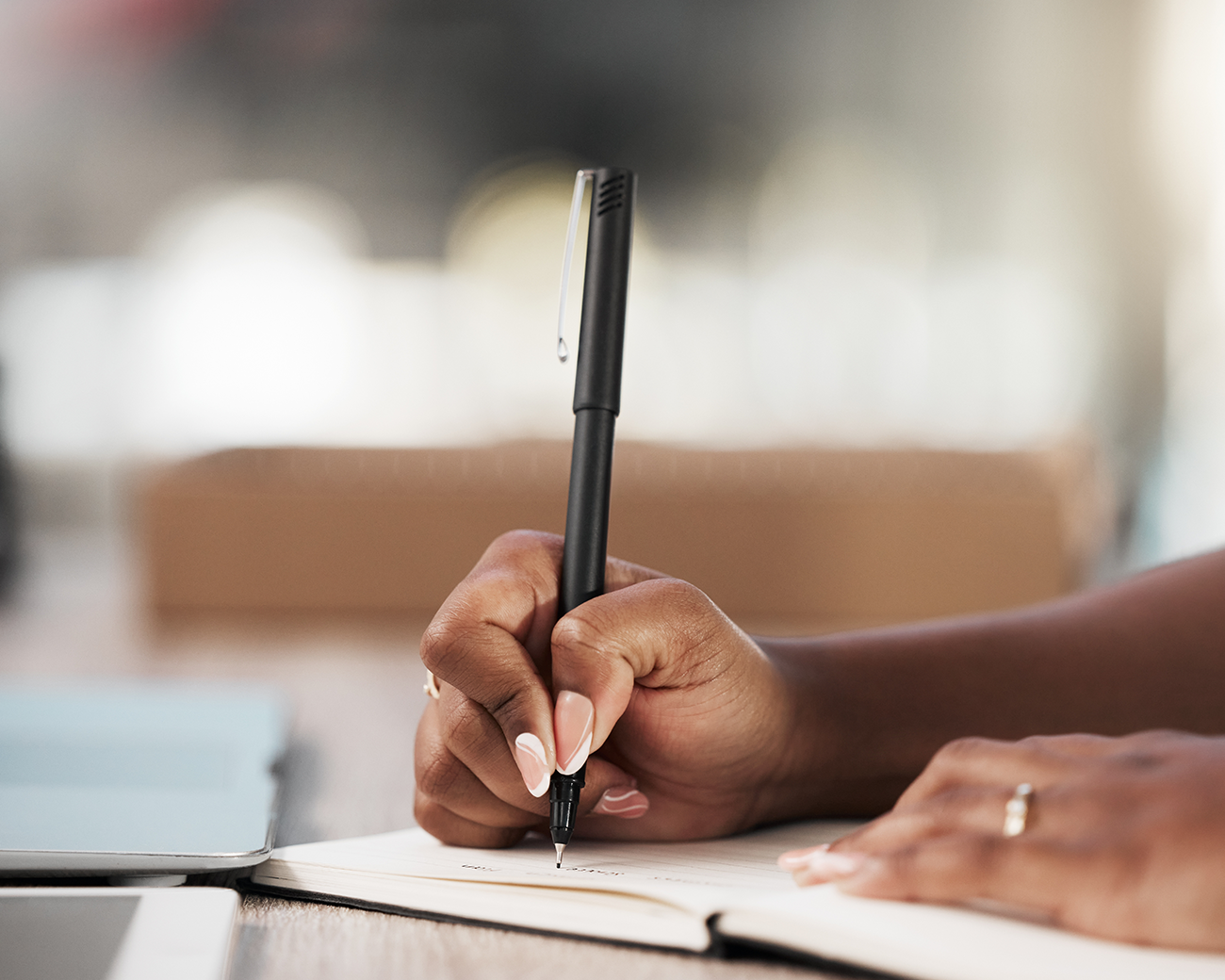 Vrouw schrijft met een pen in een notitieboek.