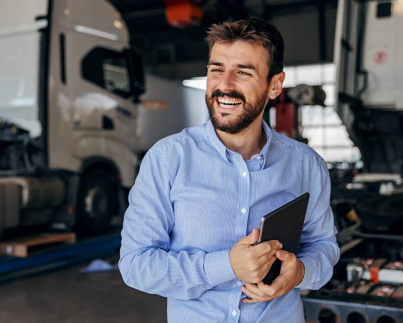 Lachende man met tablet in hand in logistieke omgeving