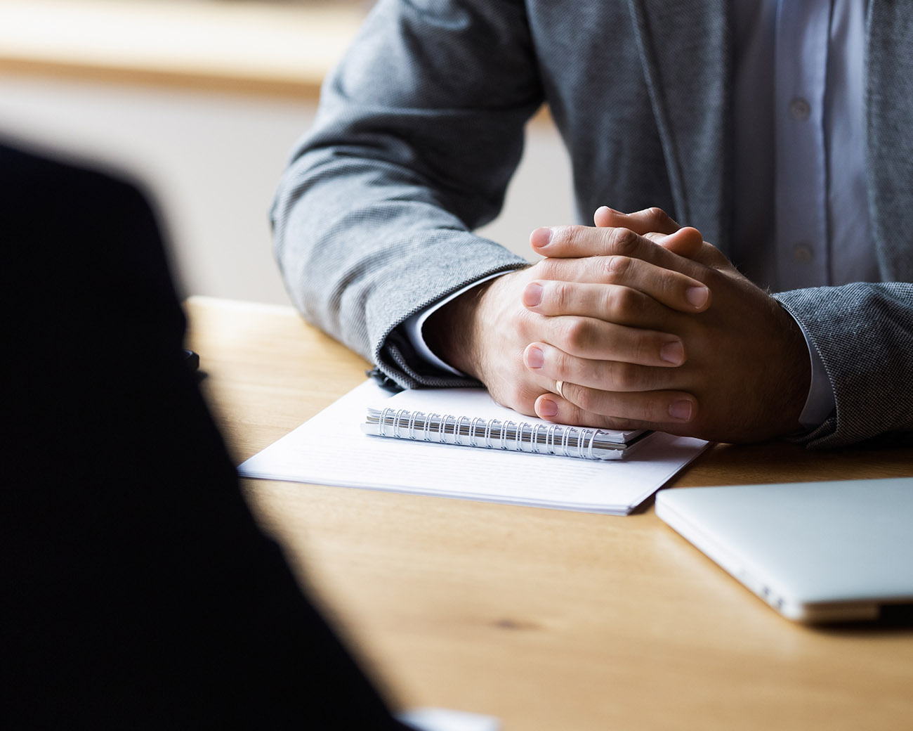 Gevouwen handen op bureau met notitieblok