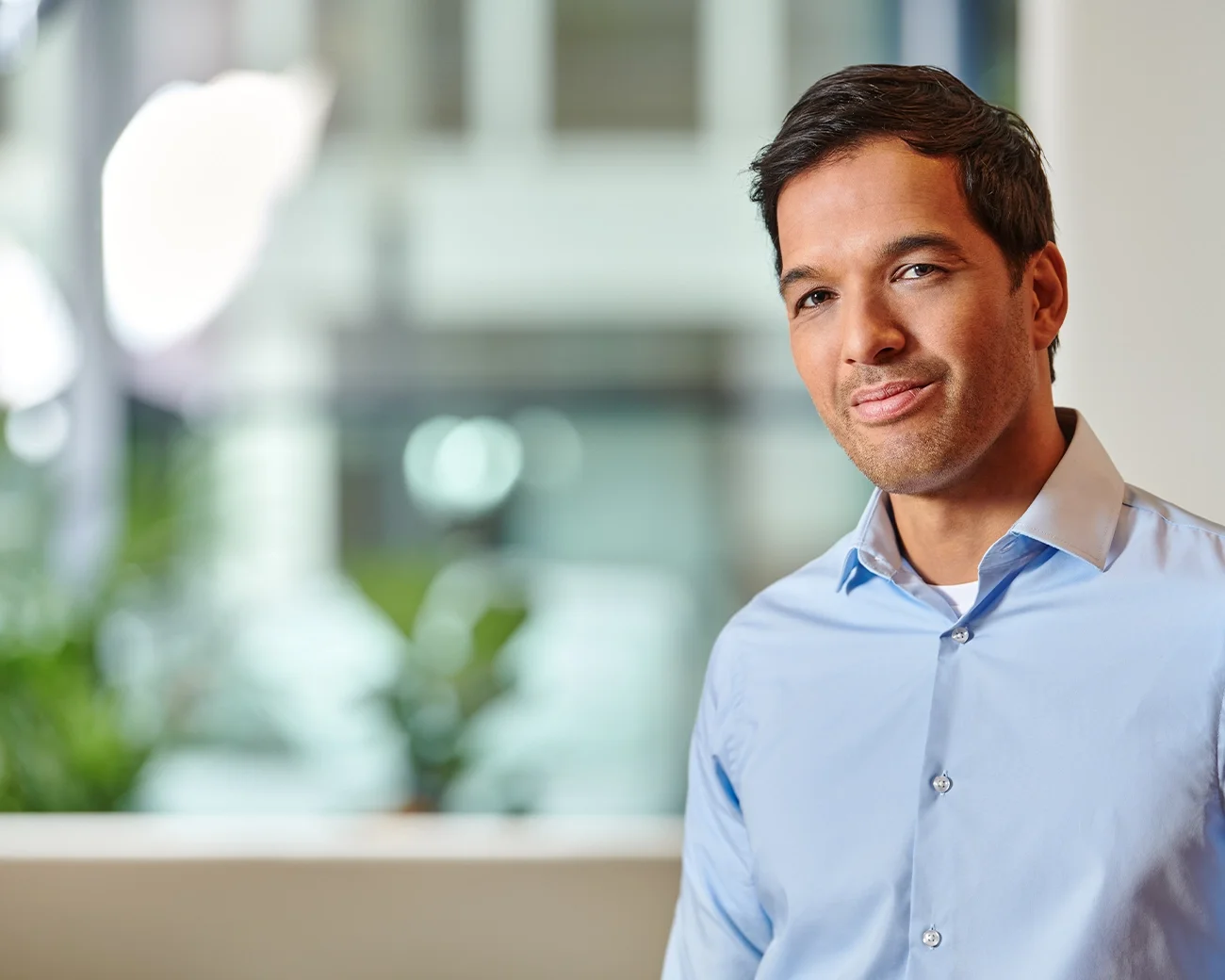 Portret van man met lichtblauw overhemd en donker haar en stoppelbaard