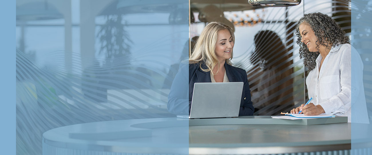 Twee vrouwen bij een statafel met een laptop en een schrift