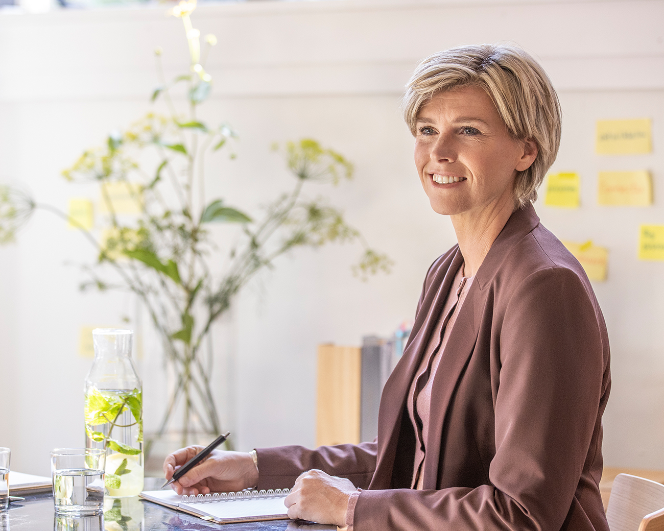 Vrouw met pen en schrift aan tafel