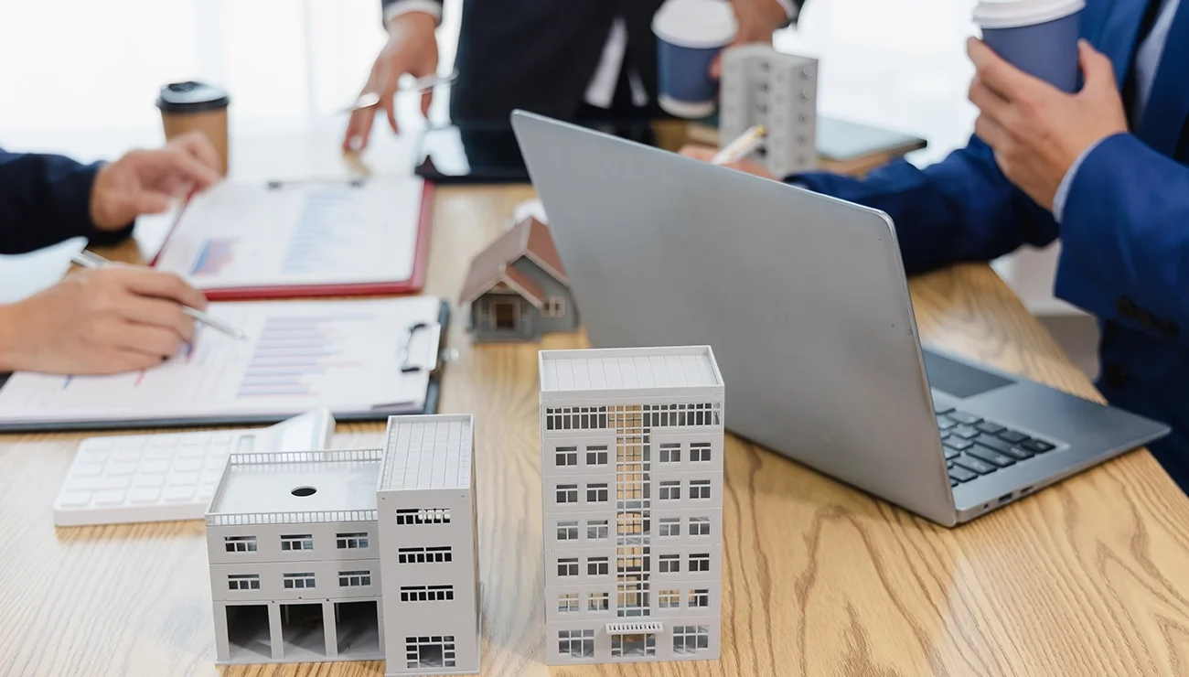 een meeting aan tafel met maquettes erop