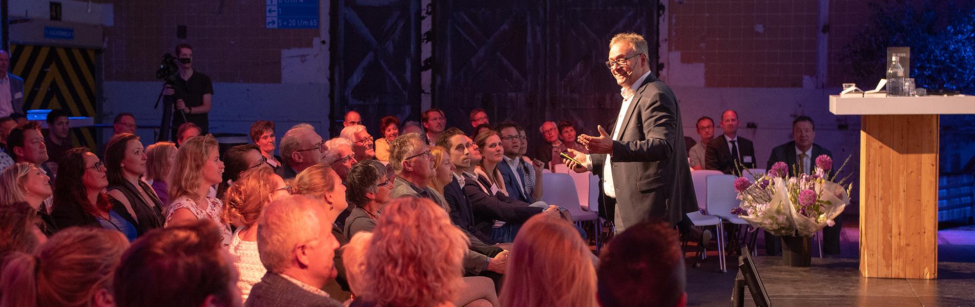 Spreker omringd door publiek op Financials Dinner