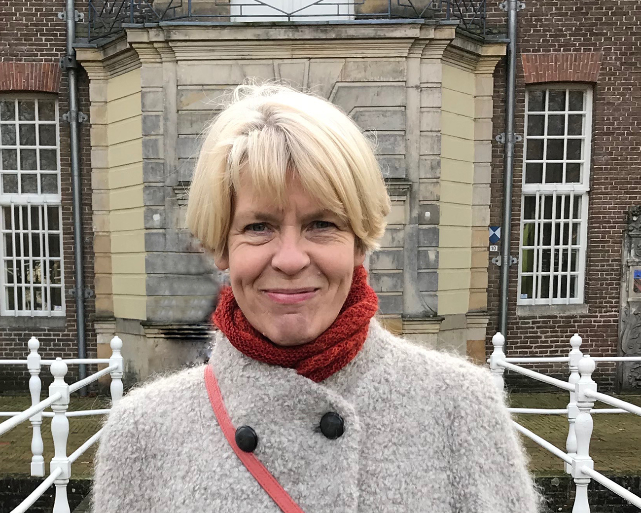 Vrouw staat op brug, kijkt in camera