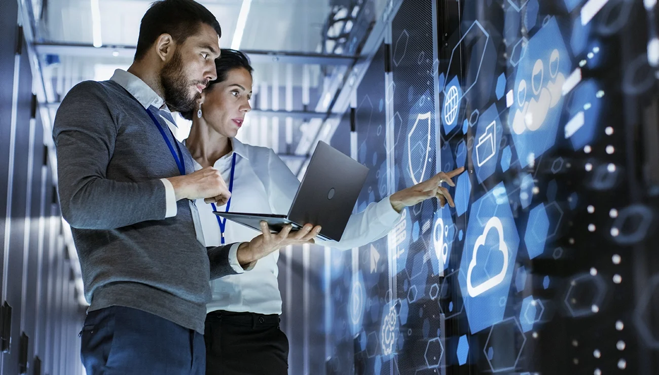 Manlijke IT-specialist met laptop overlegt met vrouwelijke servertechnicus in datacenter