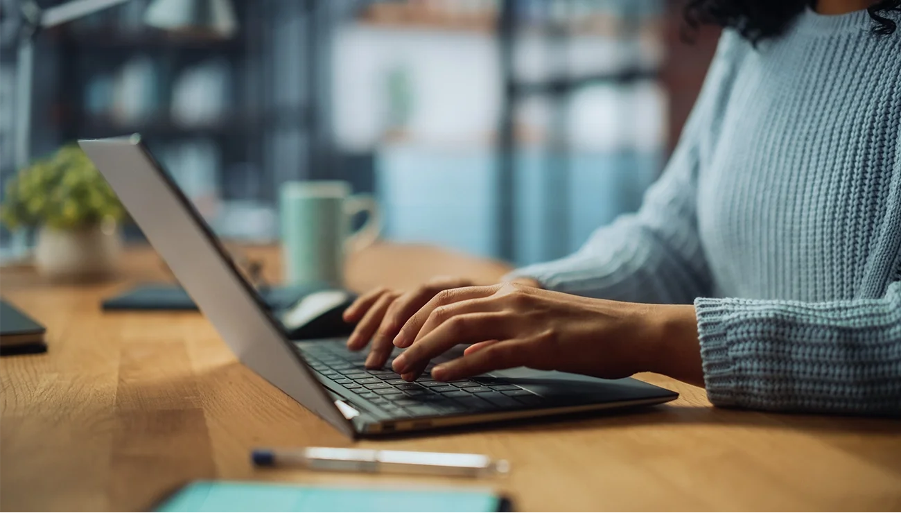 Persoon typt op een laptop aan een bureau