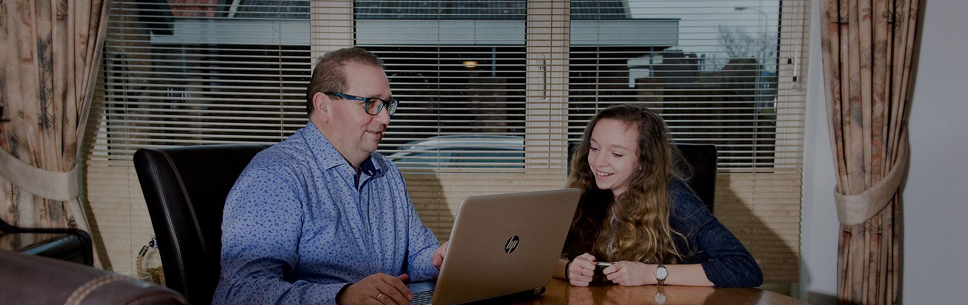 Man zit samen met zijn dochter achter een laptop