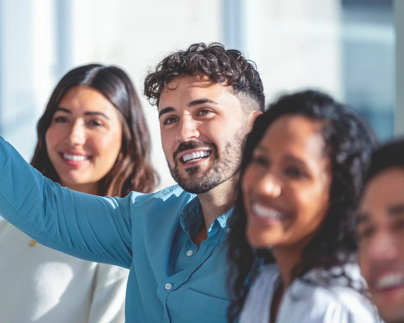 mensen in een klas lachend, een iemand steekt zijn hand op 
