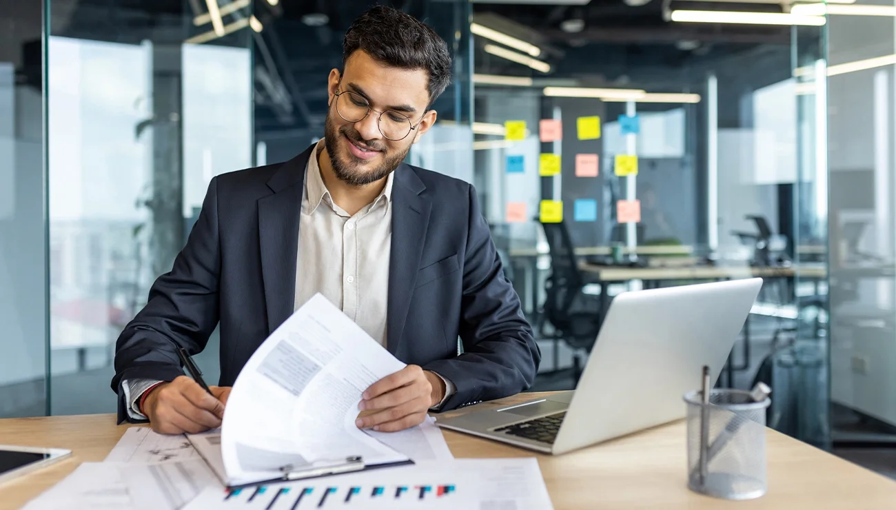 Man aan het werk achter de laptop met papieren
