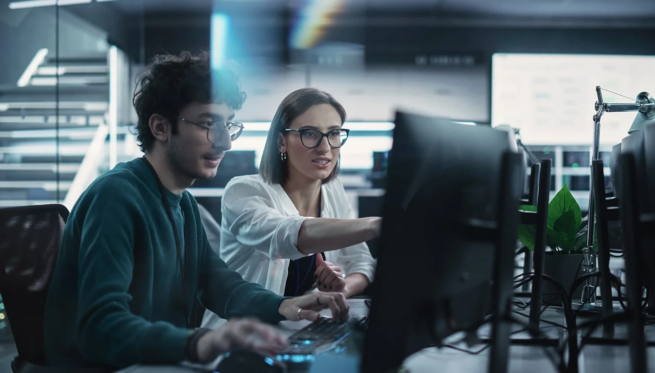 Twee jonge collega’s werken op computers en overleggen