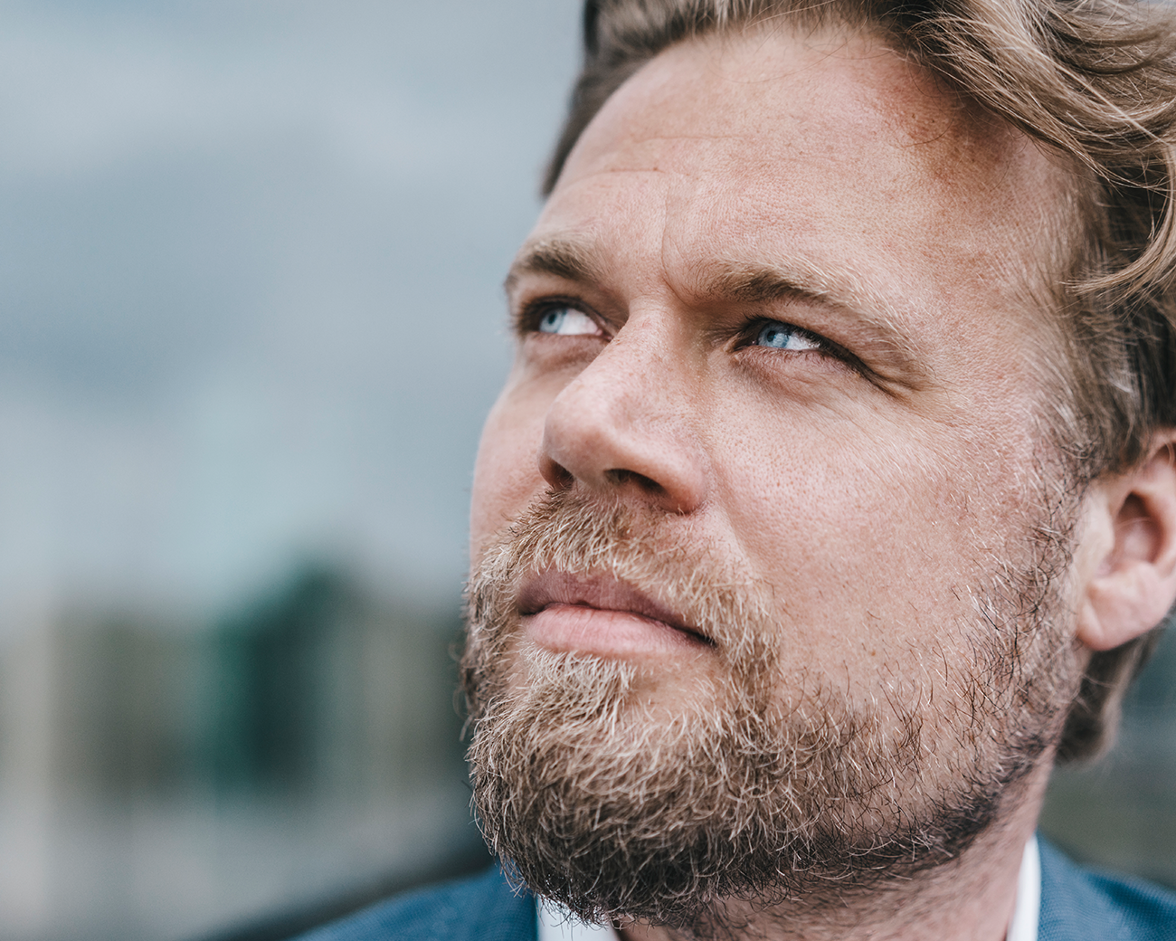 Close-up van man met blonde baard die nadenkend naar boven kijkt