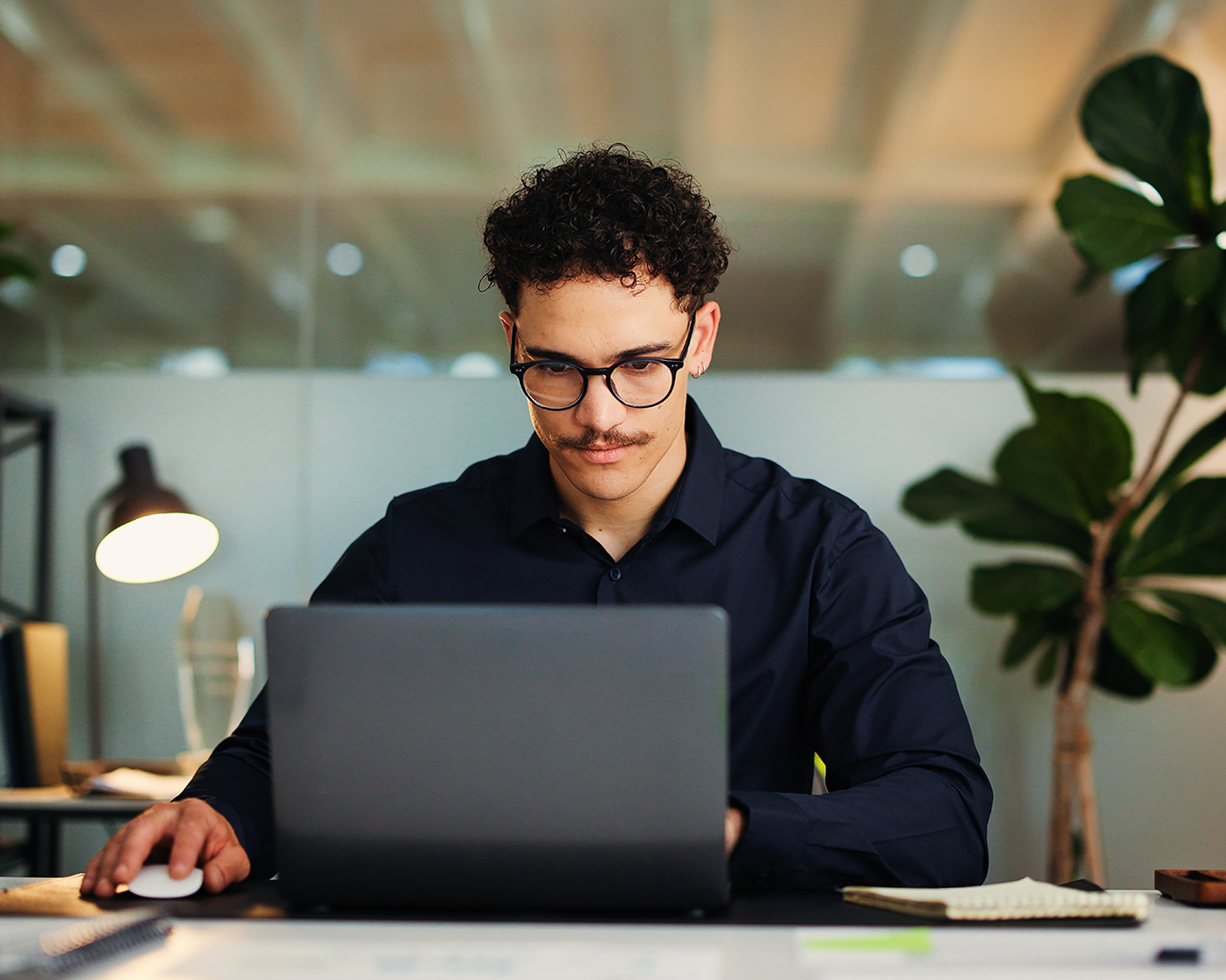 Jonge man met bril werkt achter laptop