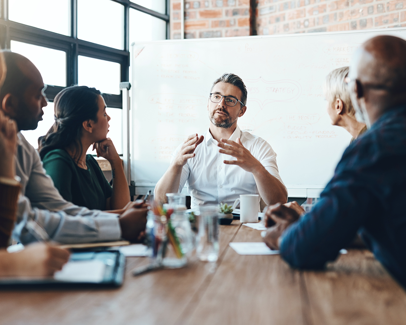 Man met zwart haar, lichtblauw hemd en rode stropdas met jasje om zijn arm kijkt recht in camera