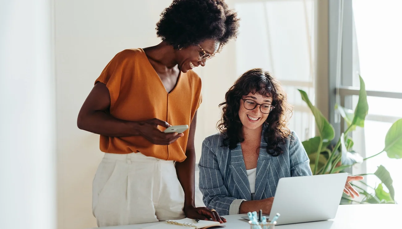 Twee vrouwen die lachend naar de laptop kijken
