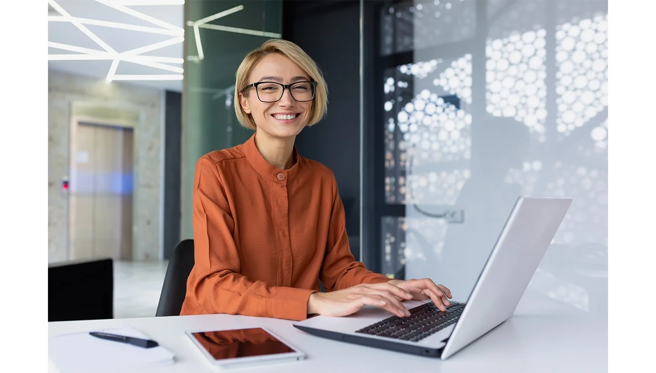 Vrolijke vrouw aan het werk achter de laptop