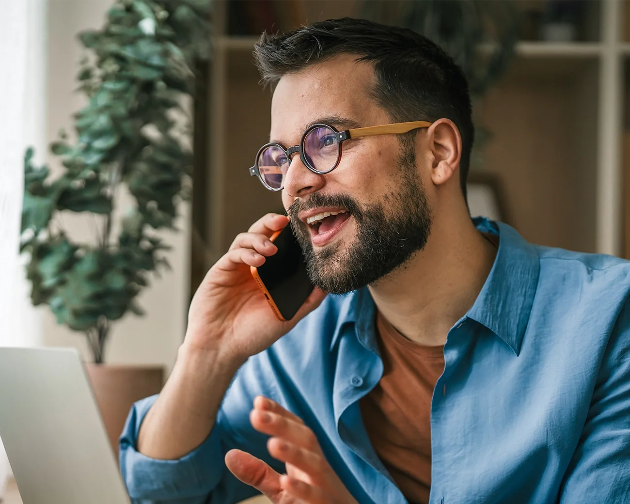 Man met bril en baard lachend aan de telefoon
