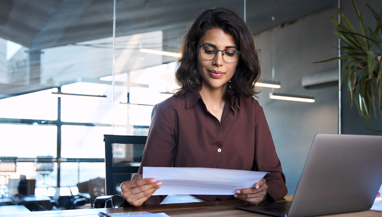 Vrouw leest papier achter laptop