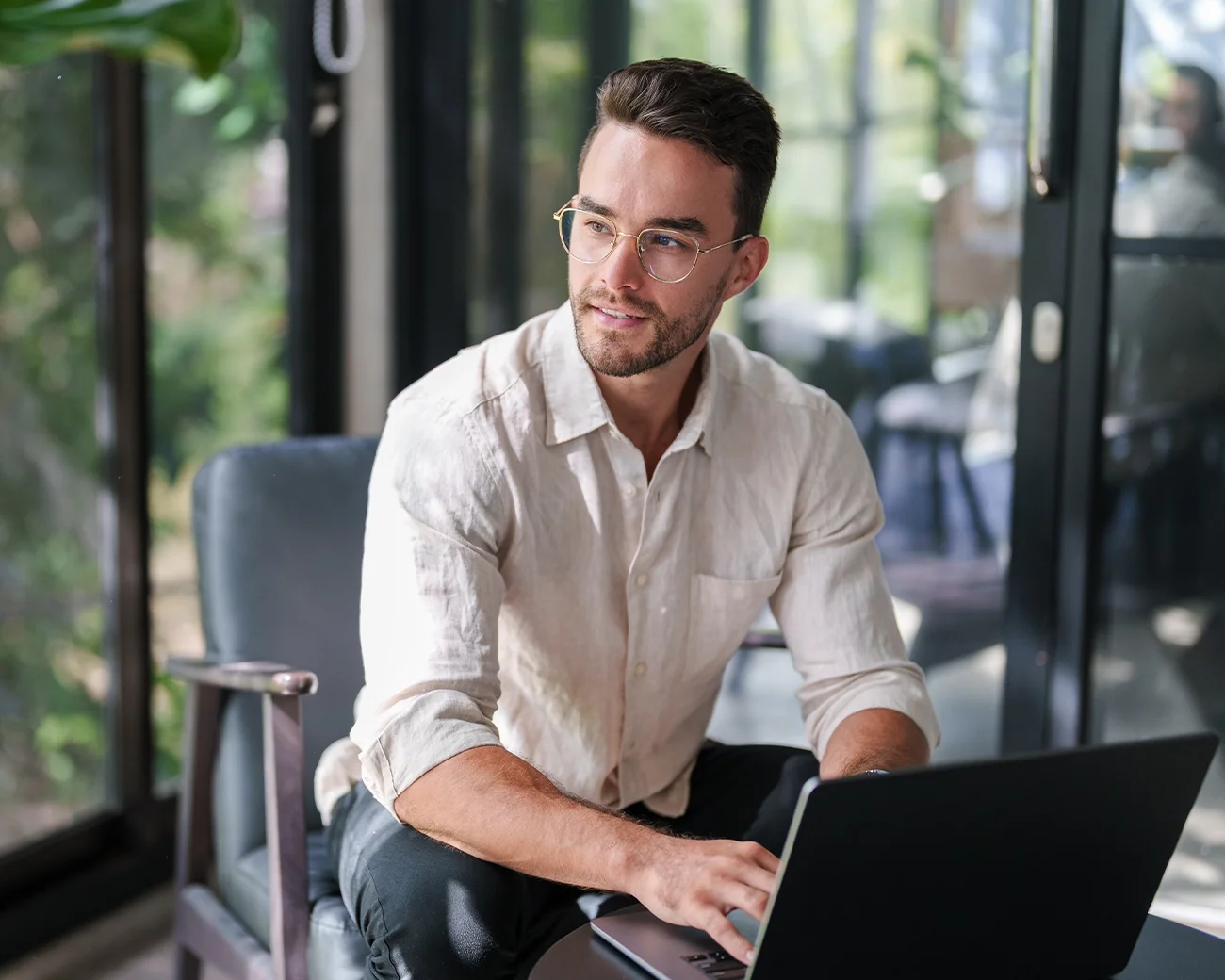 Man zit achter laptop en kijkt uit raam
