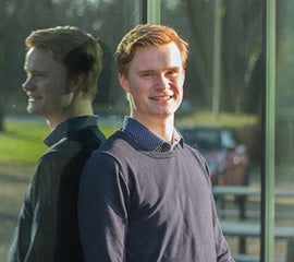 Lars van Wieringen buiten voor een gebouw met weerspiegeling in de ruit