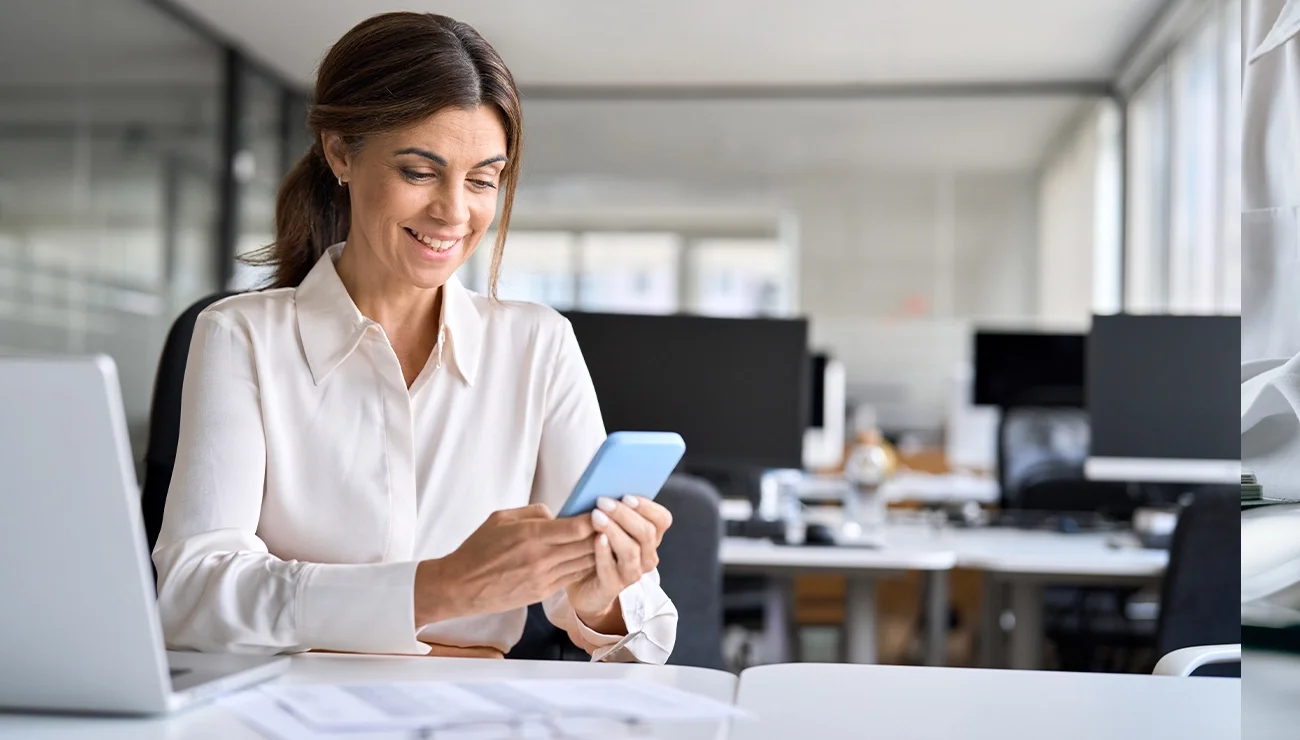 Vrouw op werkplek kijkt naar haar telefoon
