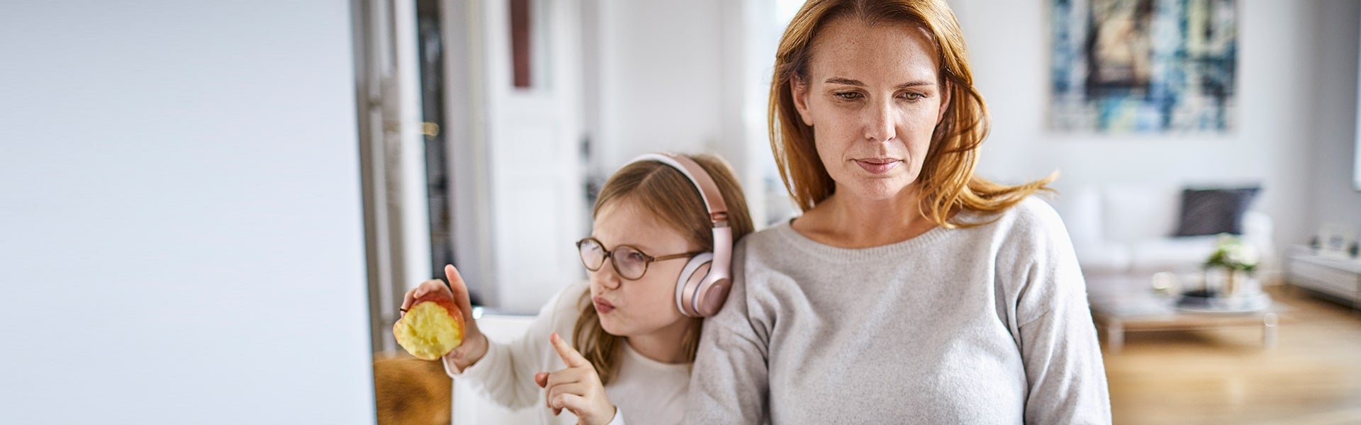 Moeder met dochter die een koptelefoon draagt en een appel vastheeft